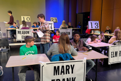 Spelling bee participants at a table with name signs.