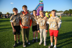 Group of young men in football uniforms posing for a picture at a sports event.