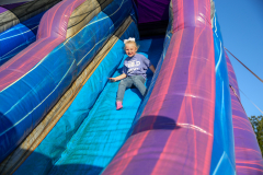 Child sitting on a slide in an inflatable play area.