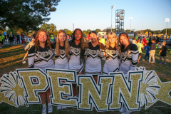 Seven cheerleaders posing in front of a sign that reads 'PENN'.