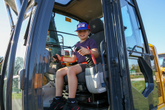 Boy sitting in a bulldozer at a construction site.