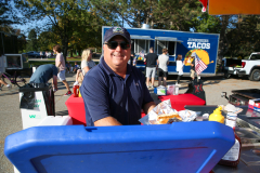 Man standing behind food truck at outdoor event.