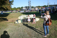 People standing in a field taking pictures of a sign that says "Hoco Expo".