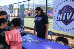 Woman standing at table with sign reading "NIVA" in front of her.