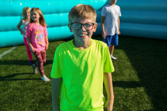 Boy wearing a neon green shirt standing on an inflatable surface.