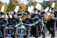 Marching band members playing instruments in formation during parade.