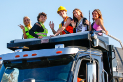 People on a truck in a parade waving to the crowd.