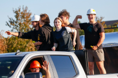 People on a float in a parade, smiling and waving, celebrating an event.