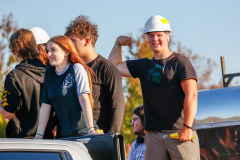 A group of people at a parade, posing for a picture in front of a truck.