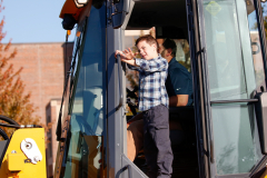 Child in a construction vehicle at a parade.