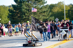 People walking down a street, carrying a flag on a float, participating in a parade.