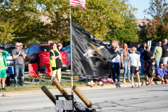 People standing around a flagpole in a parking lot.