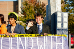People standing near a sign that says 'caution' in a parade.