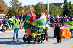 People standing in street holding signs, one says "Penn Theatre", others are walking by.