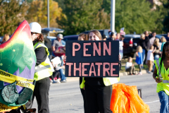 People gathered at Penn Theatre during a parade, holding signs and participating in the event.