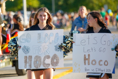 Two girls holding signs at a parade, one says "Hoco" and the other "Congrats 2010".