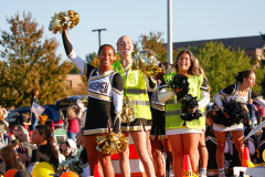 Three cheerleaders celebrating on a float during a parade.