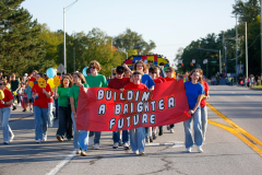 People walking in a parade holding a banner that says "build a brighter future".