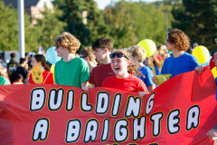People at a parade holding a sign that reads 'building a brighter future'".