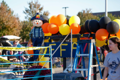 Vibrant halloween float with clowns, balloons, and a truck in a parade.