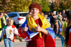 The person is holding a flag and giving a thumbs up.