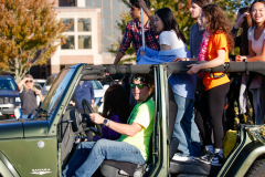 People riding in a jeep during a parade.