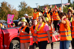 Group of people in orange vests standing by a truck, celebrating at an event.