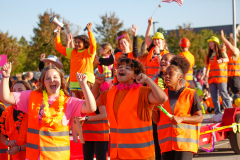 People in orange vests celebrating at a parade.