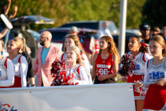Group of cheerleaders in red and white uniforms standing on a field.
