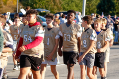 Football team in uniforms walking together on a field.