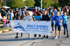 People holding a banner at a parade, proudly representing walt disney elementary school.