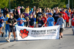 Children walking in a parade holding signs.