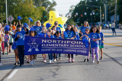 Group of people posing on street with sign that reads "Northpoint Elementary School Home of the Suns" and a large inflatable