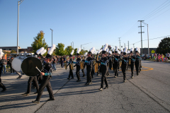 Band members in uniforms marching down street during parade.