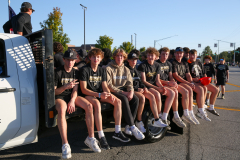 Team of young men posing on a truck at a parade.