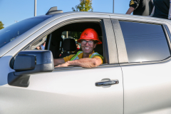 Man in a pickup truck wearing a hard hat, smiling at the camera.