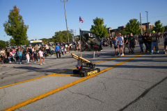 Parade float with a cannon in the middle of a street.