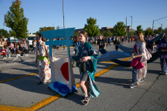 People in costumes walking down a street during a parade.