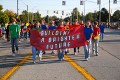 People walking in a parade holding a banner that says "Build a brighter future".