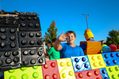 Person in front of Lego-themed float at parade.