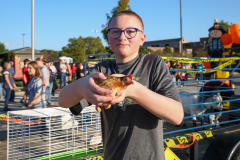 Person holding a chicken at a fair.