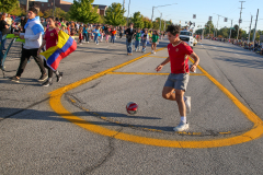 Soccer player kicking a ball on street during parade.
