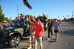 Group of people walking in a parade, holding flags and banners, celebrating an event.
