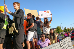 This is a collage of four photos from a halloween parade featuring people in costumes and holding signs.