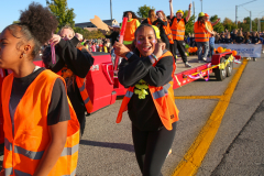 Group of people in orange safety vests standing on a street.