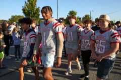 Group of football players in uniforms walking together on a street.