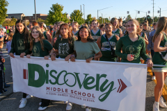 Group of cheerleaders posing for a picture in front of a banner at a parade.