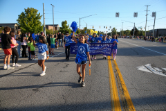 People participating in a parade, walking down a street.