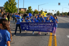 Group of people in a school parade holding signs and balloons.