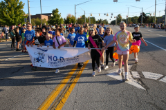 Group of people on a street holding signs and banners, participating in a parade.